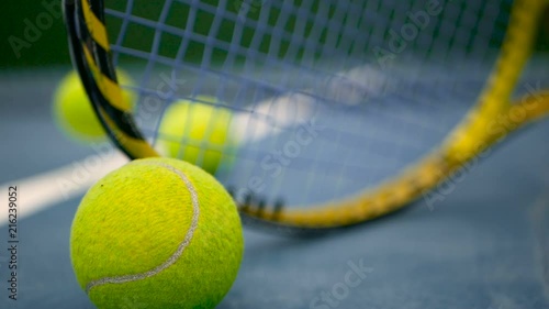 Close up of tennis equipment on the court. Sport, recreation concept. Yellow racket with a tennis ball in motion on a clay green blue court next to the white line with copy space and soft focus. photo