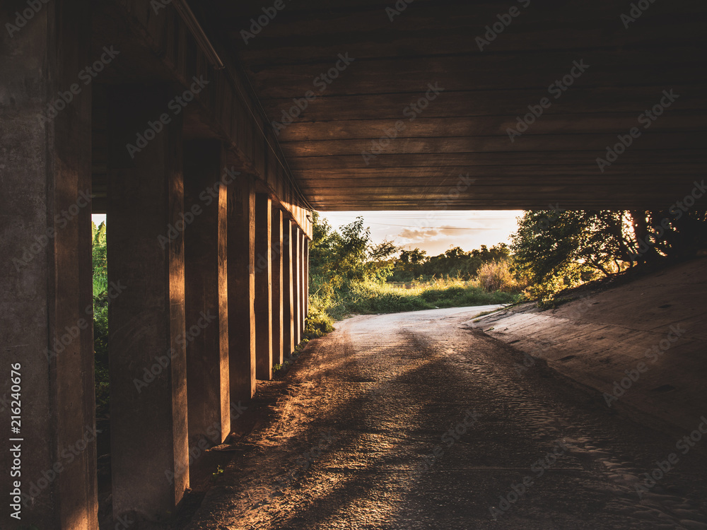 Sun shines under the bridge ,Way u-turn under road with bridge pillar,A lonely place at night.