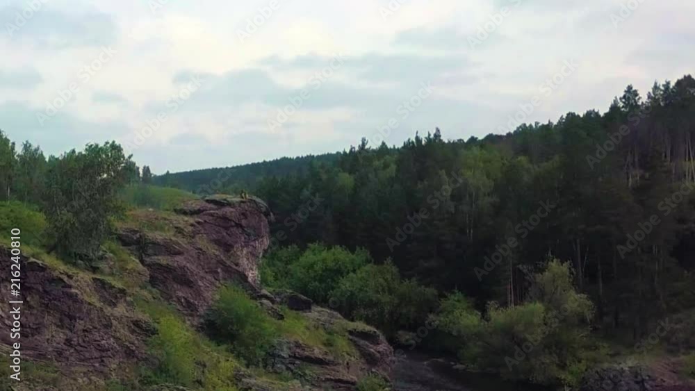 A sniper with a rifle sits on top of the mountain and inspects the territory. View from the drone. the camera moves to the soldier. A sniper with a rifle sits on top of the mountain and inspects the territory. View from the drone. the camera moves to the soldier.