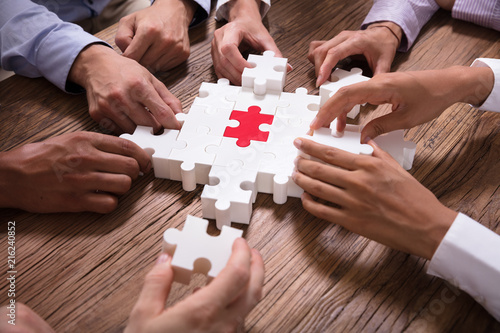 Elevated View Of Businesspeople Solving Jigsaw Puzzle