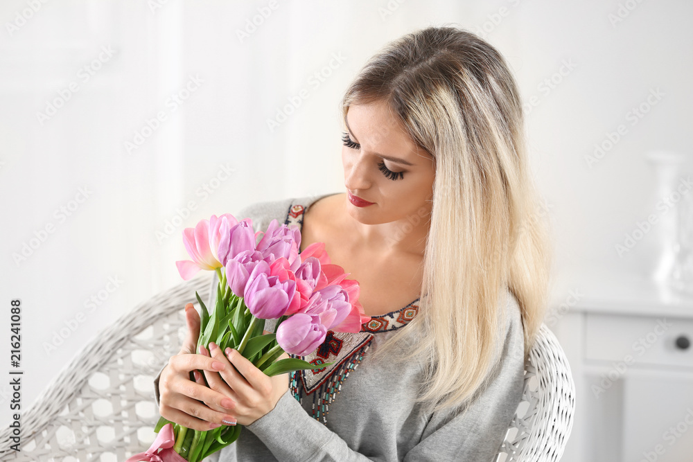 Beautiful young woman with bouquet of tulips at home