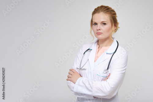 Portrait of a beautiful blonde girl doctor standing on a white background