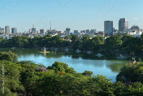 Hoan Kiem lake or Sword lake  Ho Guom in Hanoi  Vietnam with Turtle Tower  green trees and buildings on horizon