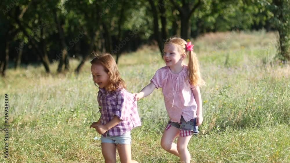 Two cute little kid girls run chase catch each other have fun in nature park slow motion Two cute little kid girls run chase catch each other have fun in nature park slow motion