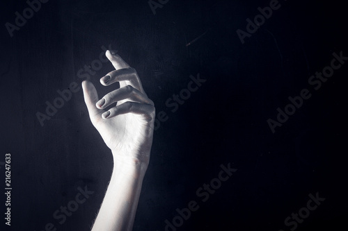 White painted hand on a black background. Abstract. Copy space