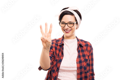 Pretty pin-up girl wearing glasses showing number three with fingers.