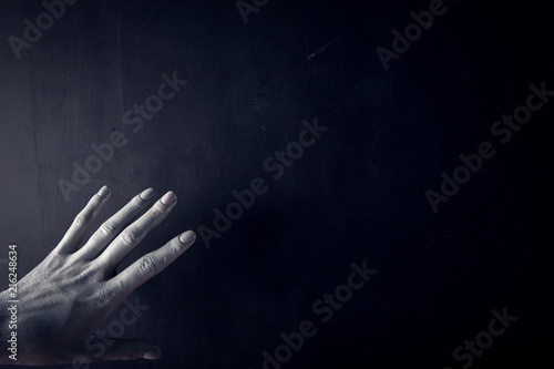 White painted hand on a black background. Abstract. Copy space