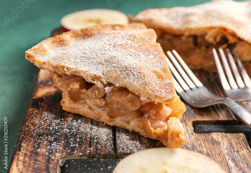 Pieces of tasty apple pie on wooden board, closeup