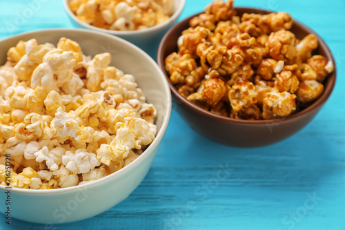 Bowls with delicious popcorn on wooden background, closeup