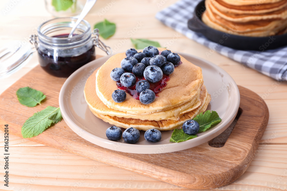 Board with tasty pancakes, jam and blueberries on wooden table Board with tasty pancakes, jam and blueberries on wooden table