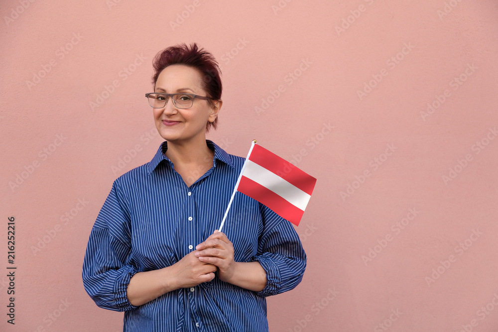 Austria flag. Woman holding Austrian flag. Nice portrait of middle aged lady 40 50 years old with a national flag over pink wall background. Austria flag. Woman holding Austrian flag. Nice portrait of middle aged lady 40 50 years old with a national flag over pink wall background.