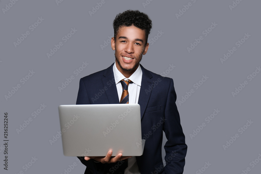 Handsome African-American businessman with laptop on grey background Handsome African-American businessman with laptop on grey background