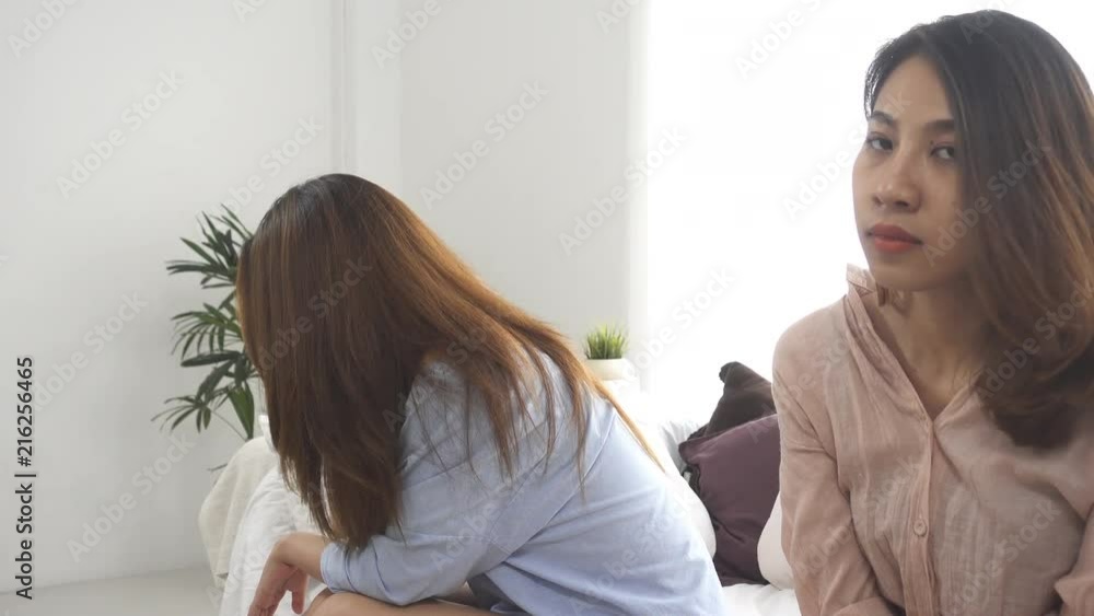 Unhappy Asian lesbian lgbt couple sitting each side of sofa with moody emotion in living room. Women conflict with her girlfriend and have bad relationship at home. Unhappy Asian lesbian lgbt couple sitting each side of sofa with moody emotion in living room. Women conflict with her girlfriend and have bad relationship at home.