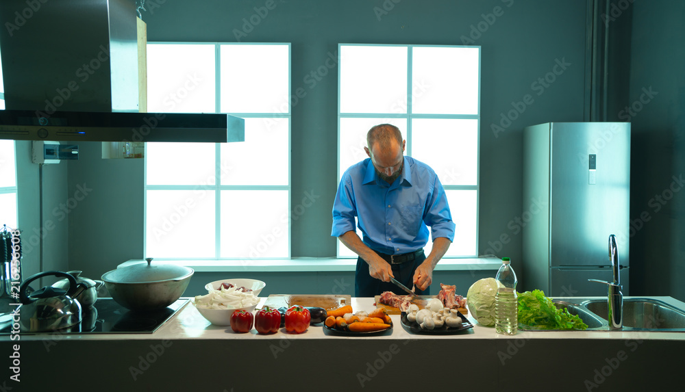 A man in the kitchen cuts meat A man in the kitchen cuts meat