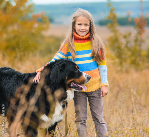 girl on walk with her four-legged friend on autumn fields Berner Sennenhund
