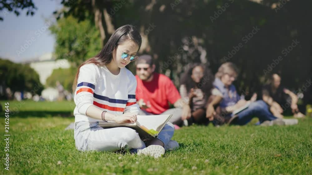 young asian girl wearing sunglasses looking through textbook young asian girl wearing sunglasses looking through textbook