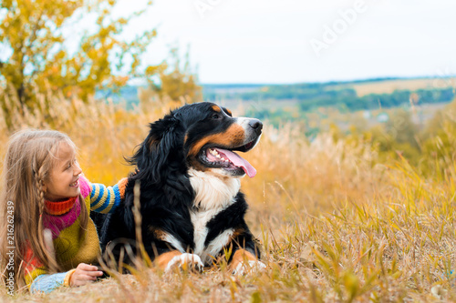 girl lies next to big dog on autumn walk Berner Sennenhund