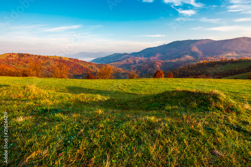 grassy meadow on hill side at sunrise in autumn. beautiful mountainous landscape with distant valley in fog
