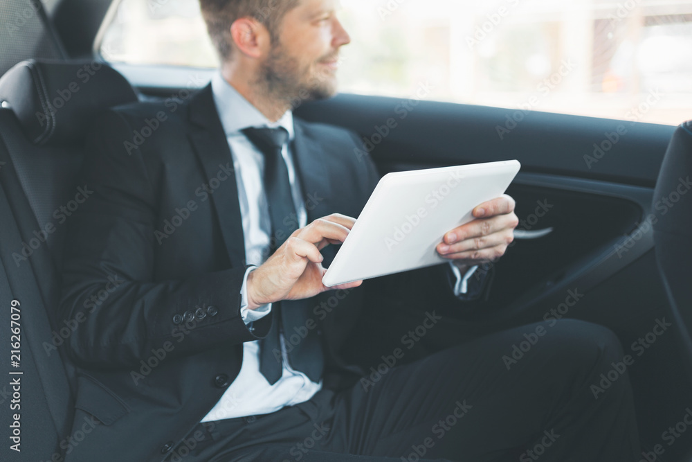 Executive businessman at the back of car using a digital tablet Executive businessman at the back of car using a digital tablet
