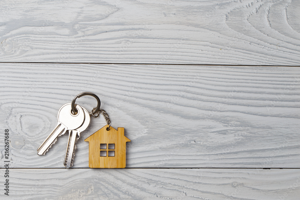 Naklejka premium House keys with house shaped keychain on wooden background