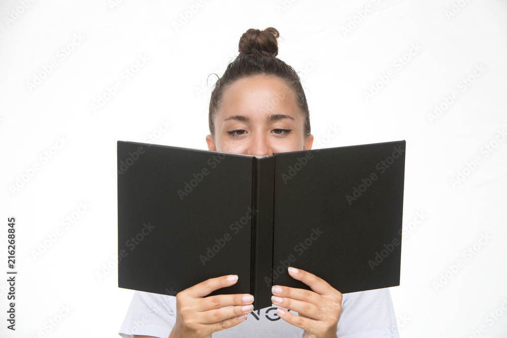 Close up portrait of a young woman student covering her face with book isolated over the white Close up portrait of a young woman student covering her face with book isolated over the white
