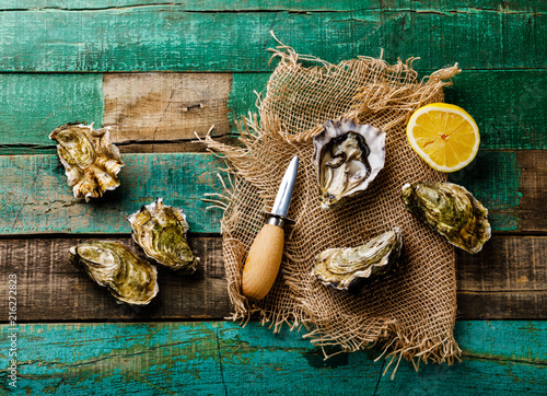 Open fresh Oysters with lemon on green wooden background photo