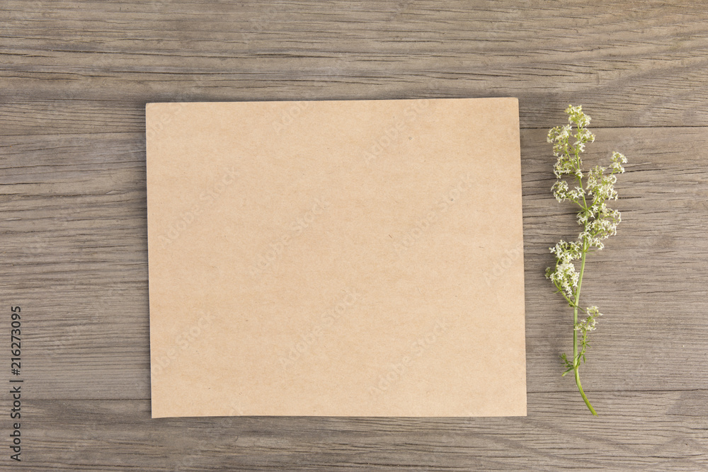 Wildflowers with craft paper blank on old grunge wooden background. Top view. Minimalistic mockup. Wildflowers with craft paper blank on old grunge wooden background. Top view. Minimalistic mockup.