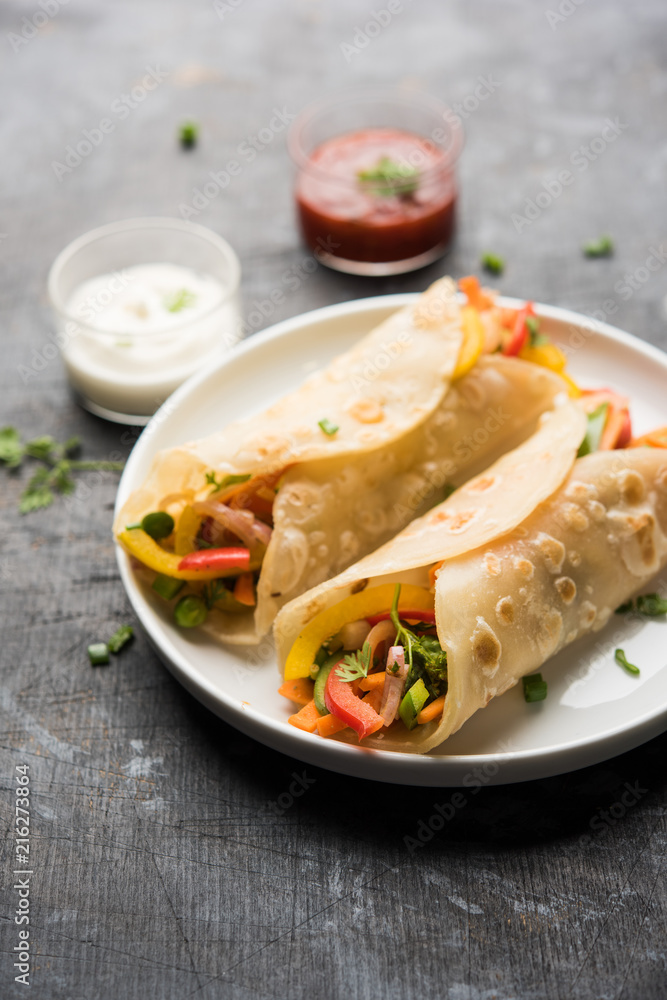 Indian Veg chapati Wrap / Kathi Roll, served in a plate with sauce over moody background. selective focus Indian Veg chapati Wrap / Kathi Roll, served in a plate with sauce over moody background. selective focus