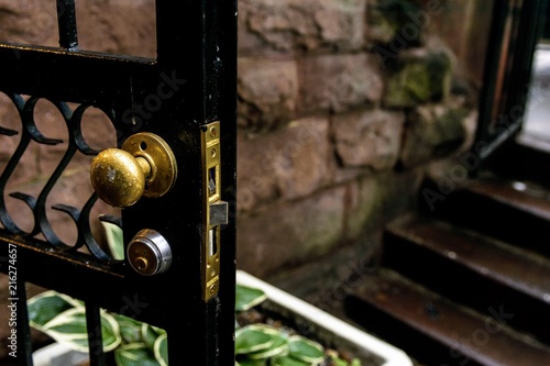 Konstfotografi Wrought Iron Door in brownstone left Open on dark and rainy day