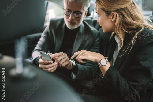 Business people using smart phone in taxi