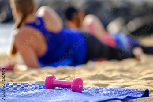 Dumbbell on the background of women doing sports on the beach 1
