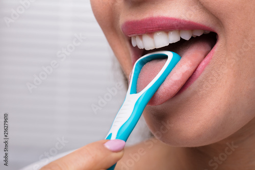 Woman Cleaning Her Tongue With Cleaner photo
