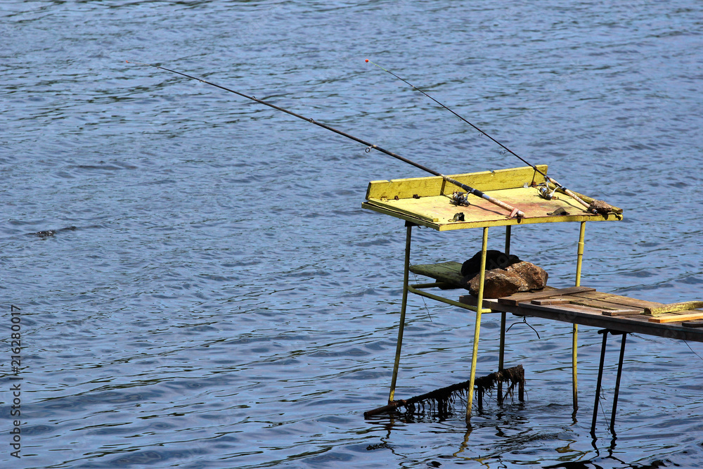 Old fishing tackle, rods with lines and reels. Angling equipment left on a self-made platform.