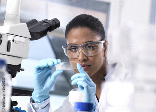 Female scientist examining a human sample on a microscope slide