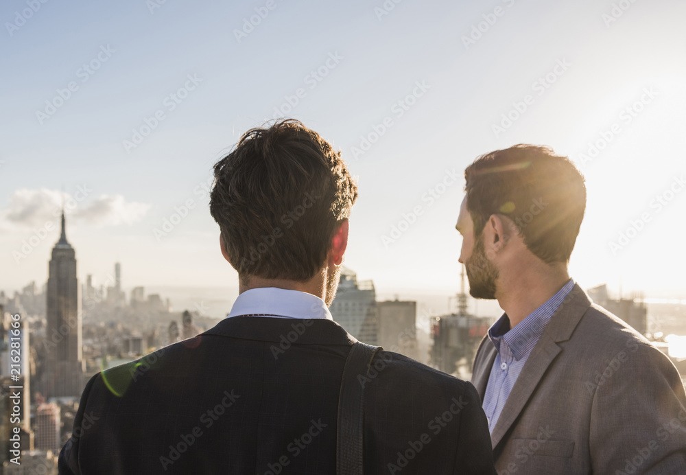 USA, New York City, two businessmen looking on cityscape on Rockefeller Center observation deck