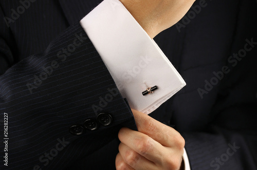 Foto Elegant young fashion man fixing a gold cufflinks