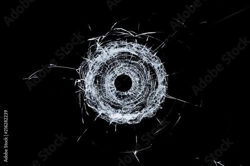 Fotografia Broken glass single bullet hole in glass isolated on black