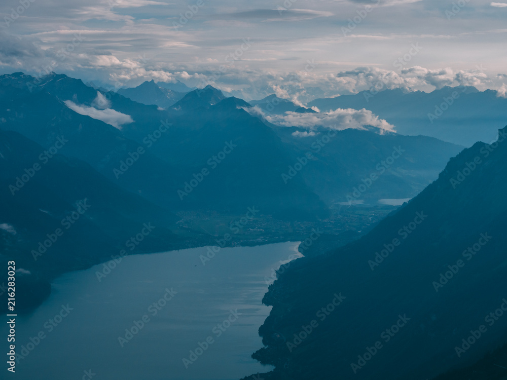 Naklejka premium view from the peak of mountain to a blue lake covered in clouds, brienzer rothorn switzerland alps