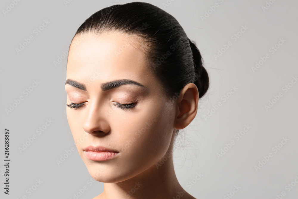 Naklejka premium Young woman with permanent eyebrows makeup on grey background