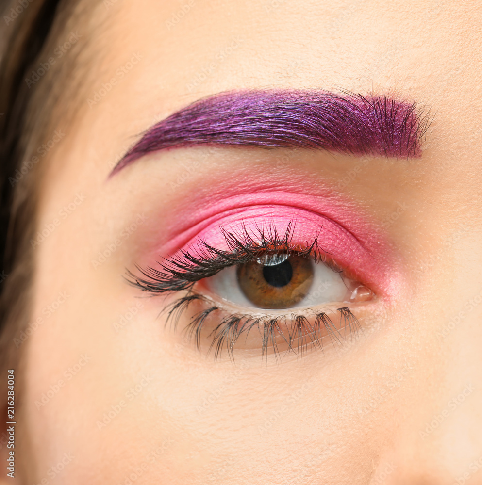 Fototapeta premium Young woman with dyed eyebrow and creative makeup on dark background, closeup
