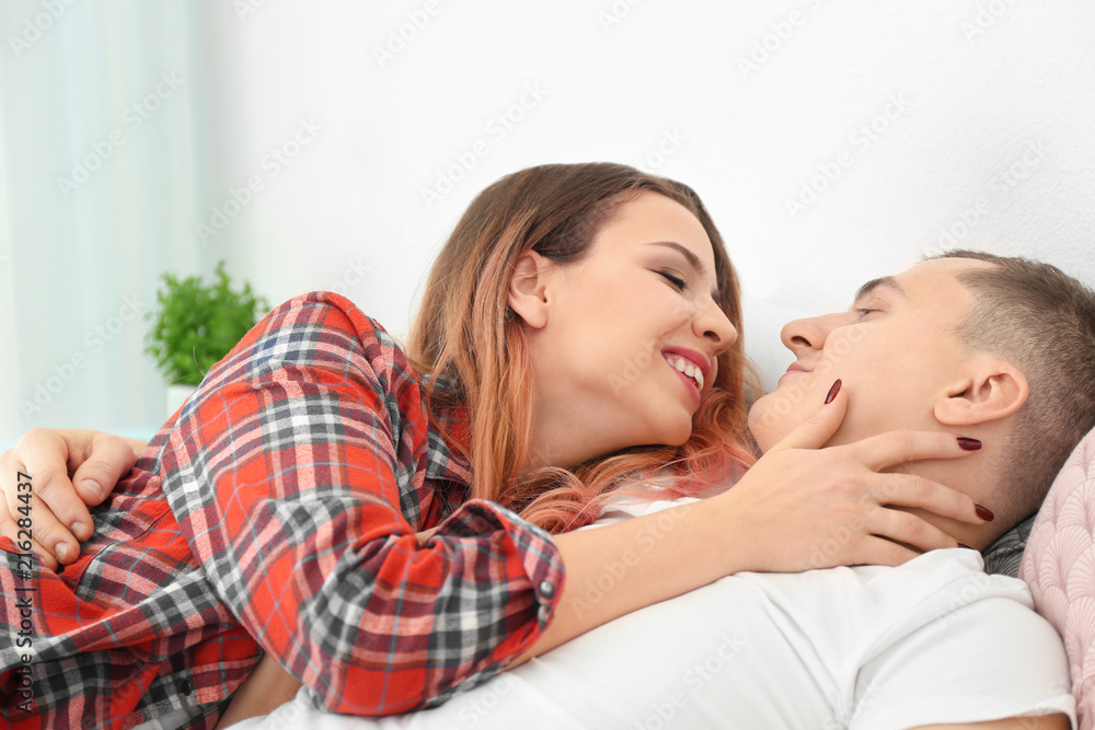 Cute young loving couple lying on bed at home Cute young loving couple lying on bed at home