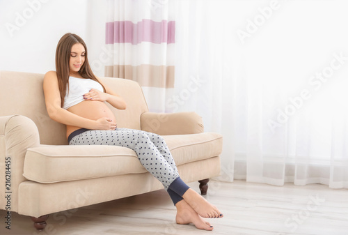 Portrait of beautiful pregnant woman resting on couch at home