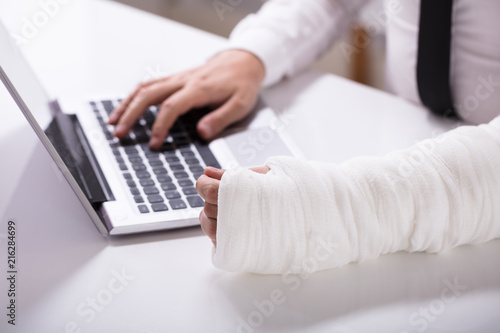 Man With Fractured Hand Using Laptop