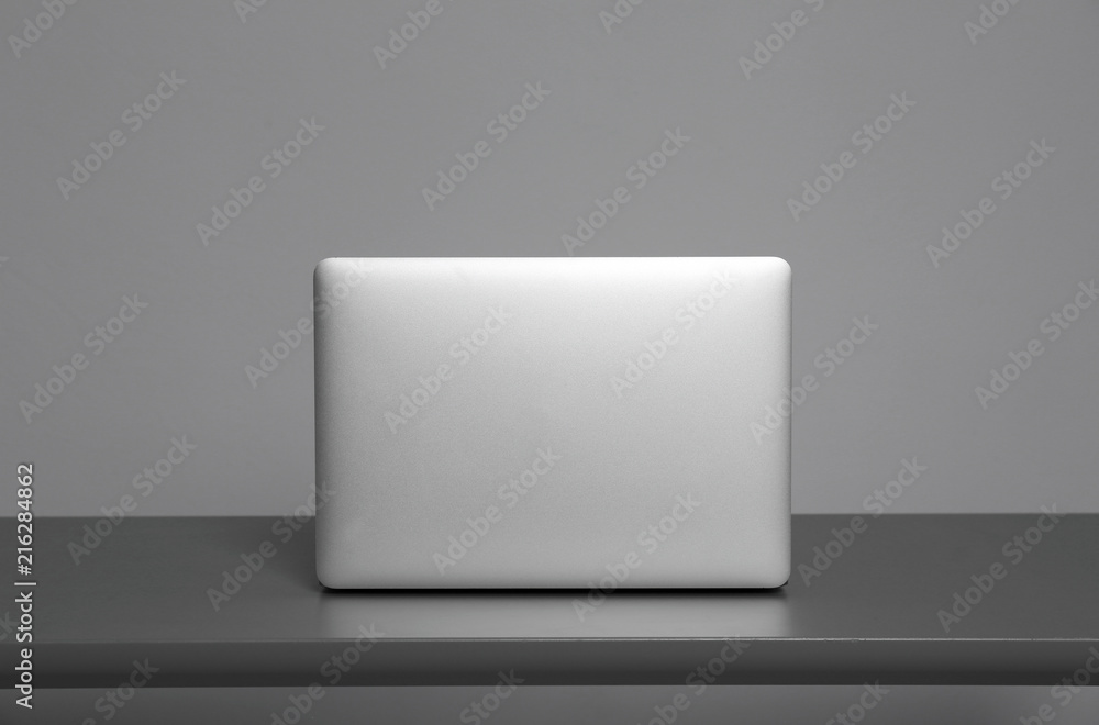Modern laptop on table against gray background Modern laptop on table against gray background