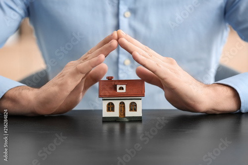 Insurance concept. Man with toy house on table
