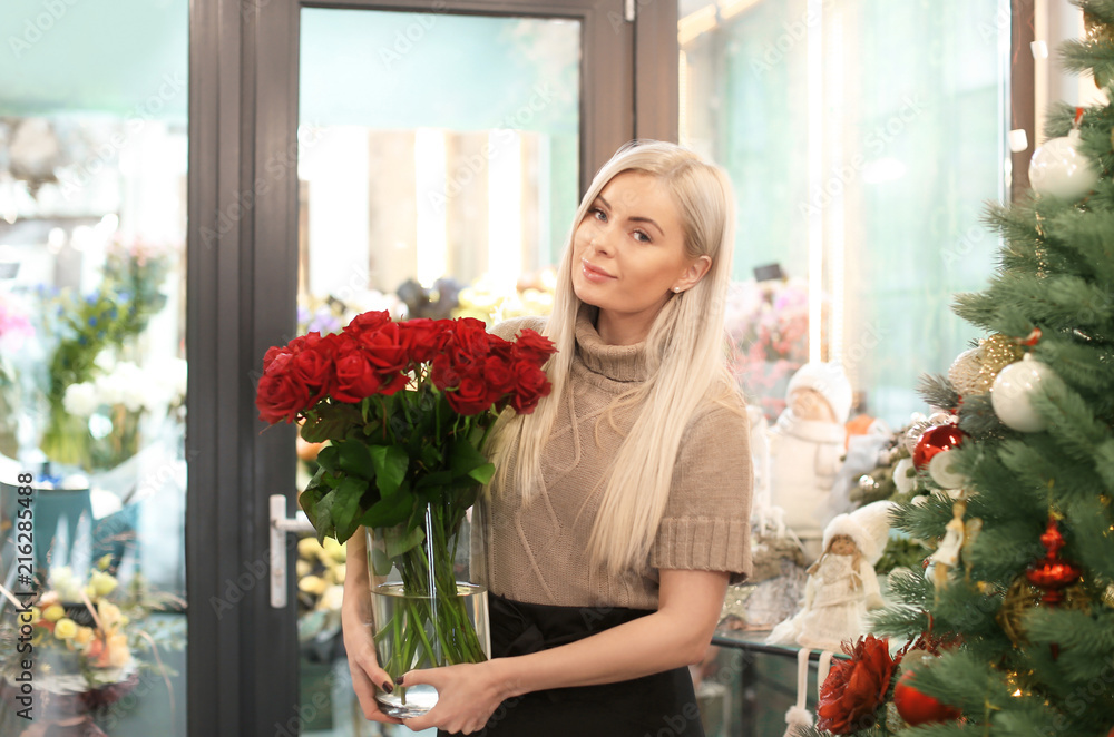 Young woman with bouquet of roses standing in store. Small business owner