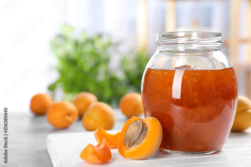 Jar with tasty apricot jam on wooden board Jar with tasty apricot jam on wooden board
