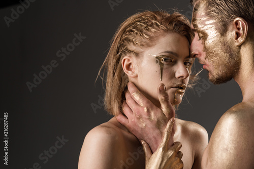 Man and woman relations. Gold spa and skincare treatment. Erotic games of couple in love. Golden collagen mask and beauty. 24K Gold. Sexy couple with golden body art makeup, copy space.