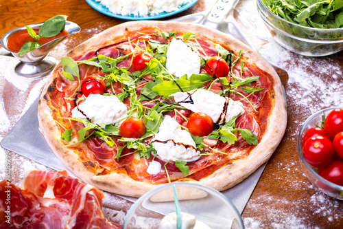 close up of delicious italian pizza with ham, mozzarella and tomatoes