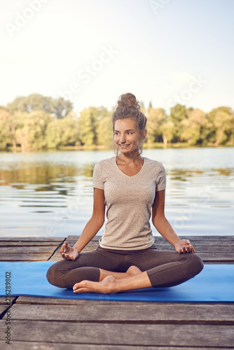 Junge Frau macht eine Yoga Übung am See